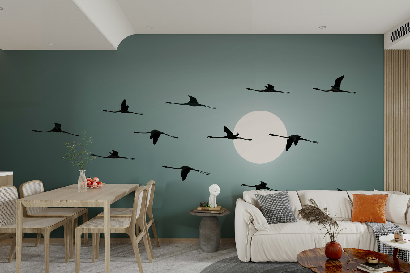 The image shows a flock of flamingos in flight, silhouetted against a large, bright circle representing the sun.

