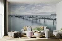 A peaceful wall mural with a long pier stretching into the sea.

