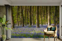 The ground is covered in a carpet of blue and purple flowers.

