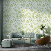 A bedroom wall covered in a subtle green printed leaves wallpaper.

