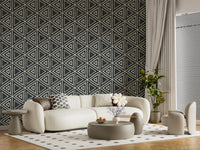 Triangle mudcloth wallpaper shapes a stylish lounge with charcoal and cream contrast.