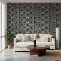 Charcoal mudcloth wallpaper grounds a cosy living room with bold cream triangle pattern.