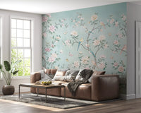 Chinoiserie aviary wall mural in living room with teal background and floral motifs.
