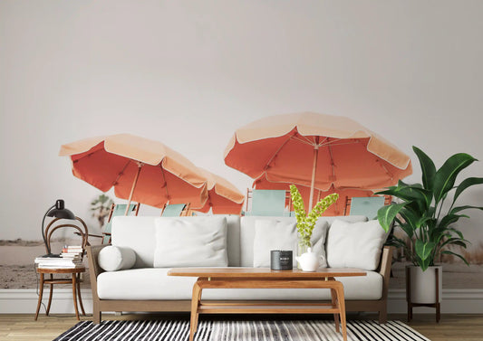Living room beach mural with coral umbrellas and seafoam tones on sandy shore. 
