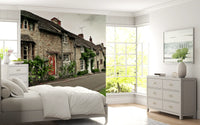 Bedroom wall mural depicting grey brick houses and white garden blossoms.
