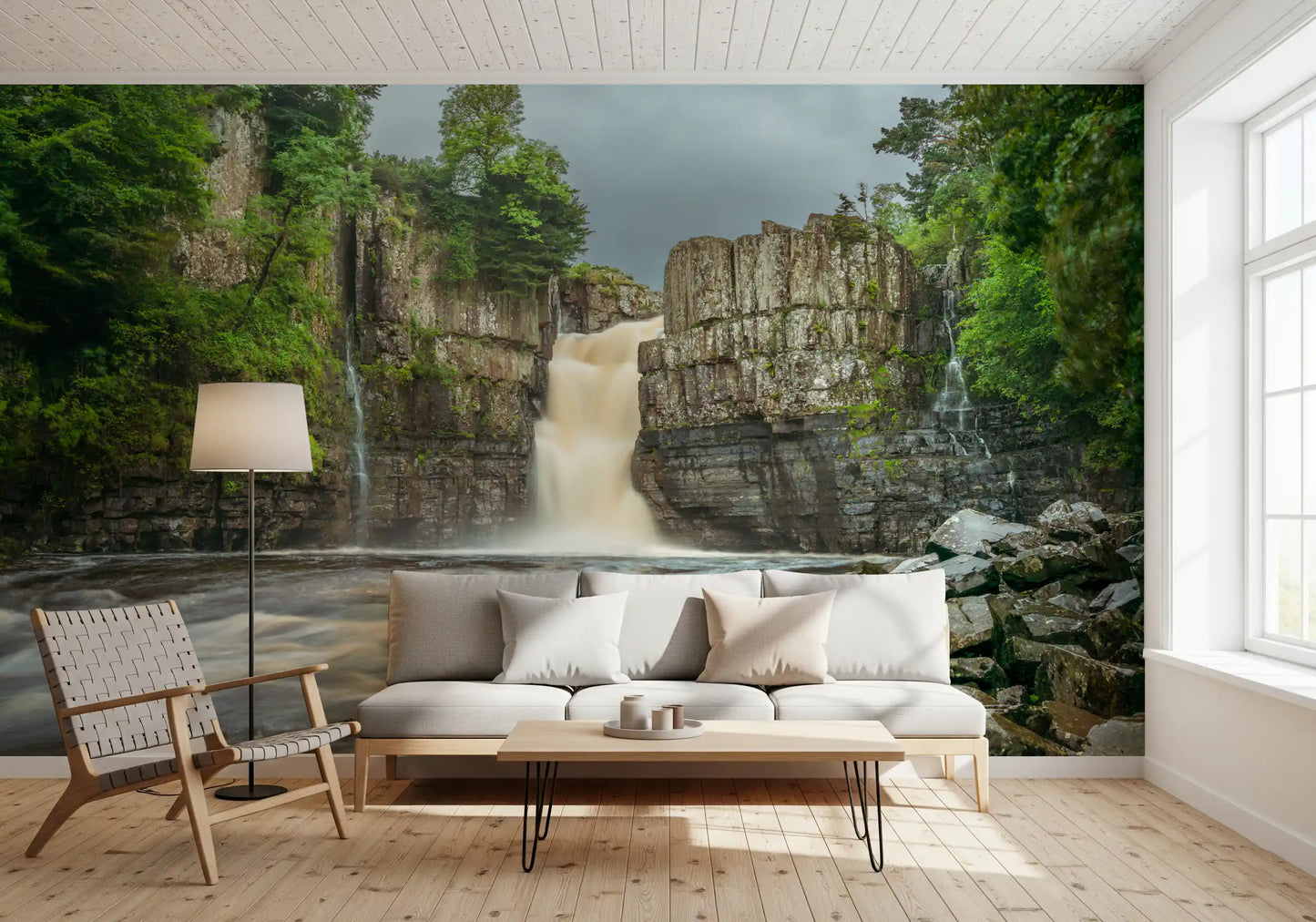 Waterfall wallpaper featuring grey stone cliffs and lush green trees for living room.