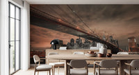Nighttime bridge wall mural with copper-colored clouds and skyscraper lights on water.