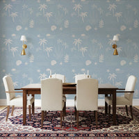 Tropical fronds and shell sketches dress a dining room in soft blue coastal wallpaper., GD9908