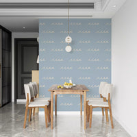 Dining room feels airy and coastal in Soft Blue Wave wallpaper with cream motifs
