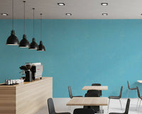 Blue linen texture wallpaper provides a cool backdrop for a cafe area.