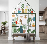 Indoor garden wall mural with a girl watering potted plants inside a green house-shaped greenhouse frame