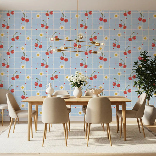 Blue gingham repeat wallpaper with illustrated red cherry pairs and white daisy motifs.