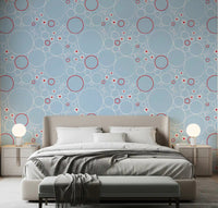 Pale blue wallpaper with white circles, red rings, daisies, and jellyfish in bedroom.