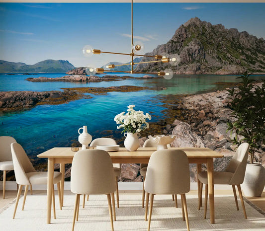Coastal mountain wall mural showing grey peaks above a turquoise bay in dining room.