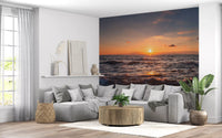 Sunset over the sea wall mural in orange, amber, and dusky blue tones.