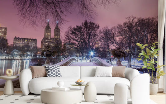 ow Bridge wall mural showing snowy Central Park at winter dusk under a pink sky in living room.