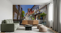 Narrow cobblestone street wall mural under a bright blue sky., GD10426