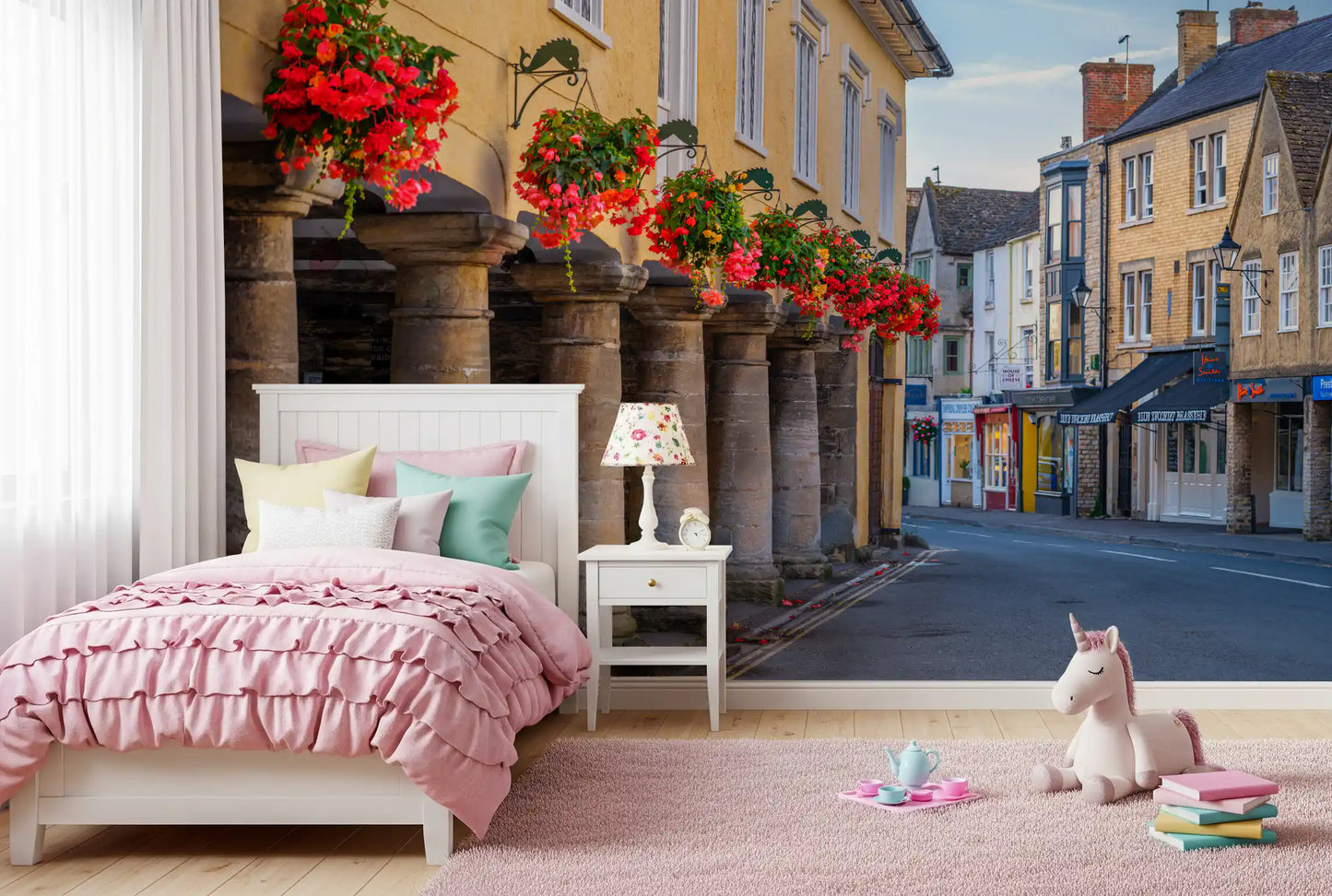 Weathered stone pillars with hanging red flower baskets in village wall mural., GD10427
