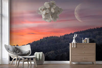 Crescent moon rising above forested slope in pink sky wall mural.