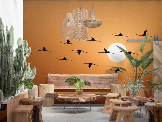 Warm orange sunset mural with flamingo flock in natural formation.