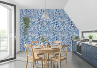 Blue and white wallpaper with full bloom roses and thorny branches in dining room.