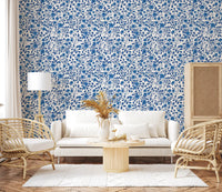 Floral repeat pattern wallpaper with blue roses and pointed blue leaves.