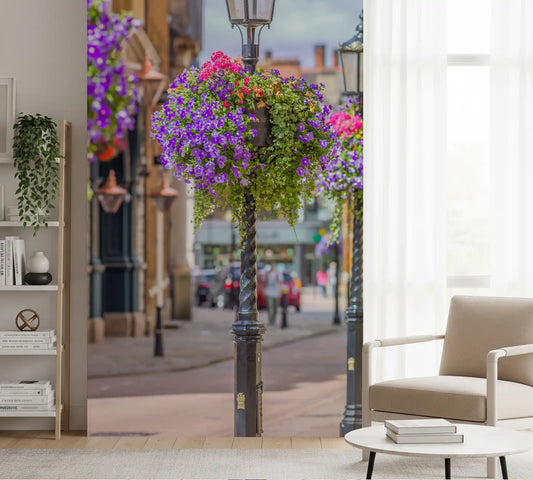 Wall mural with black lamp posts and purple flower baskets on a paved street GD11435