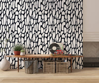 Organic monochrome pebble wallpaper above a wood console table with plants GD12223