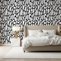 Monochrome pebble abstract wallpaper behind a beige upholstered bed in a bedroom GD12223