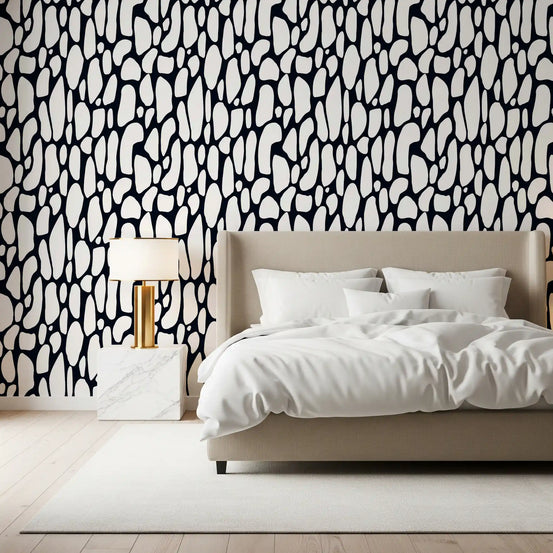 Monochrome pebble abstract wallpaper behind a beige upholstered bed in a bedroom GD12223