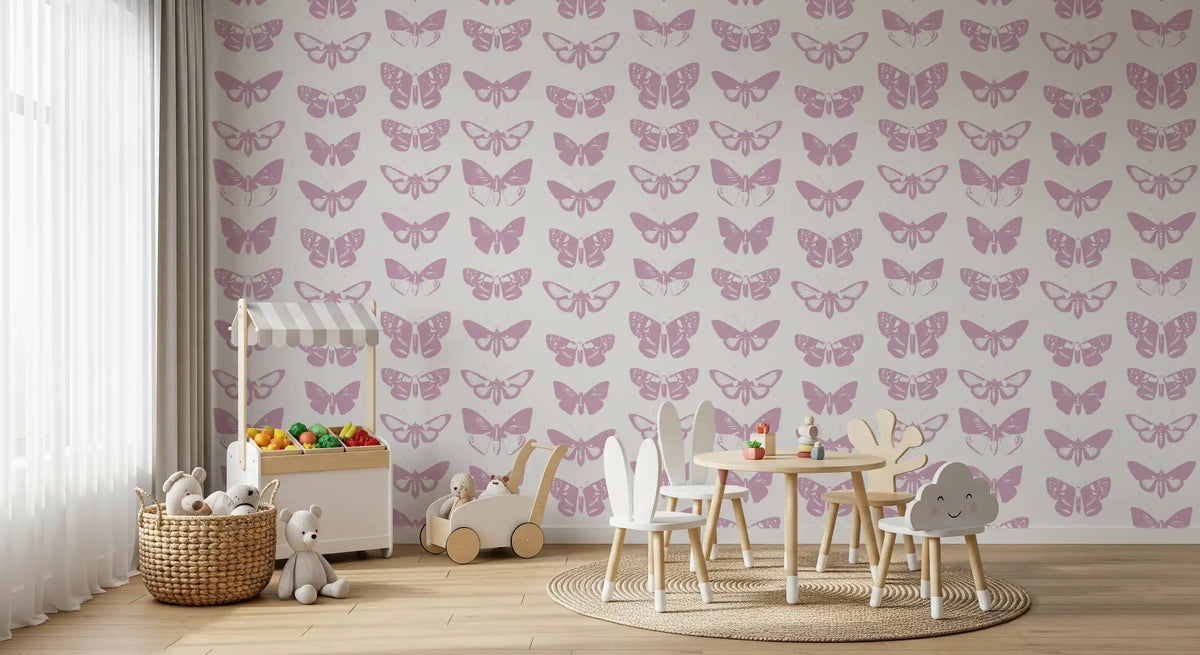 Pink butterfly wallpaper in a kids room with a play table and toy trolley GD12294