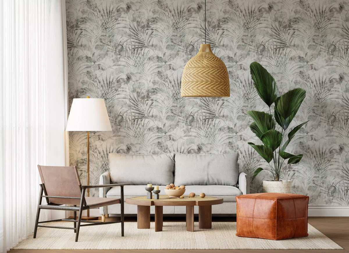Muted tropical foliage wallpaper in a living room with rattan chairs and a leather pouf GD12351