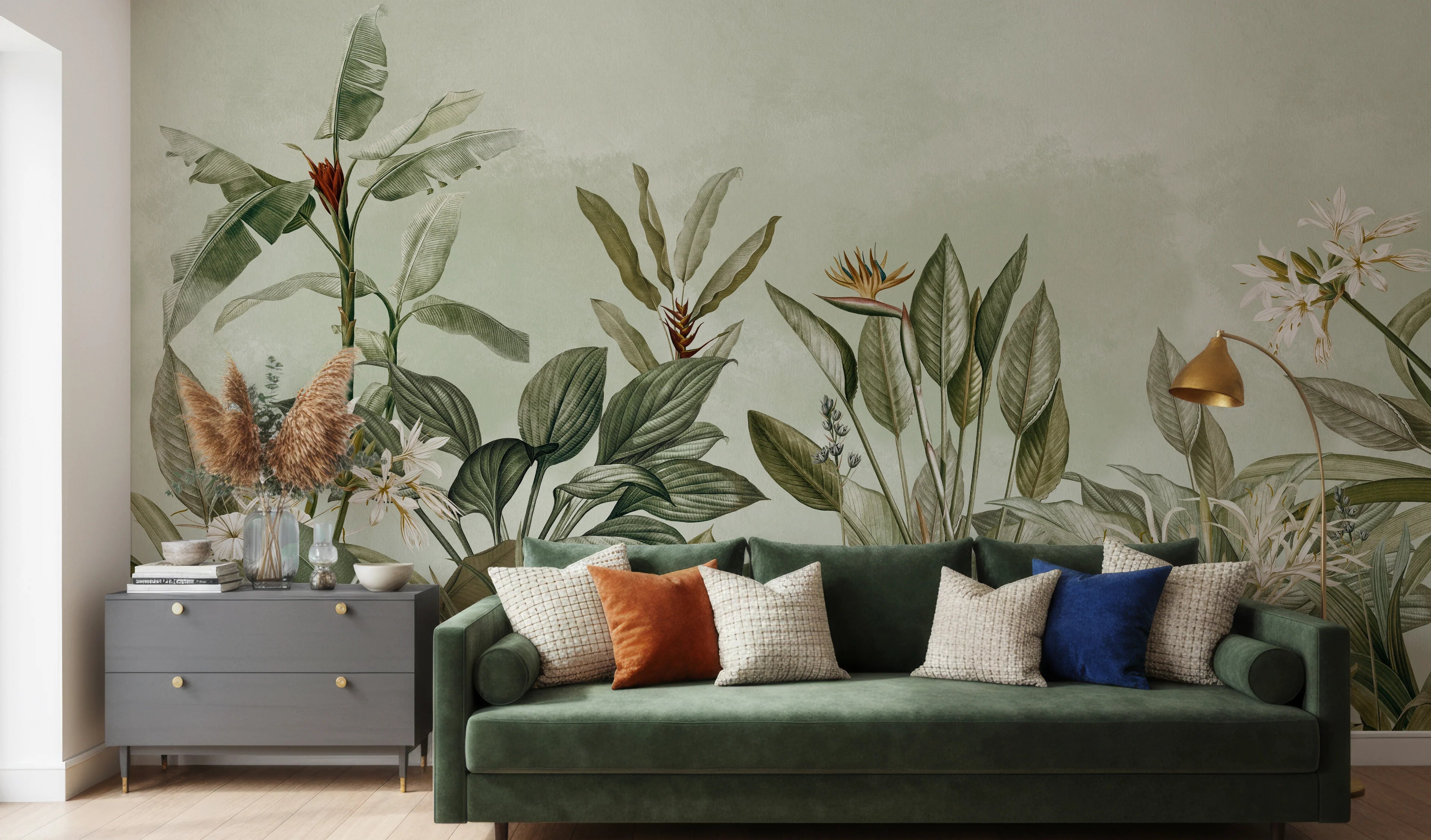 Green sofa with colorful cushions against a wall with floral wallpaper