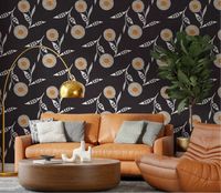 Warm lounge corner anchored by charcoal floral wallpaper and soft caramel seating