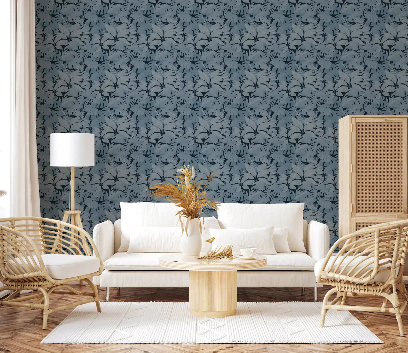 Indigo Botanical Monstera Leaves Wallpaper behind a white sofa in a bright lounge