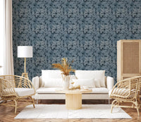 Indigo Botanical Monstera Leaves Wallpaper behind a white sofa in a bright lounge
