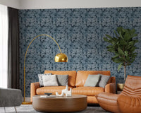 Rust sofa corner paired with Indigo Botanical Monstera Leaves Wallpaper
