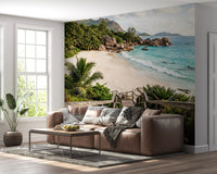 Tropical beach wall mural feature wall behind a low platform sofa with rattan armchairs in a coastal living room (GD9622