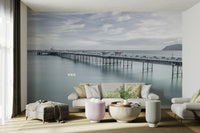 A peaceful wall mural with a long pier stretching into the sea.

