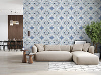 Mediterranean Indigo Fleur Tile Wallpaper behind a cream sofa in a bright lounge