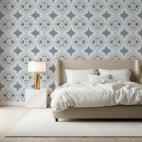 Mediterranean Indigo Fleur Tile Wallpaper in a softly lit bedroom with white bedding