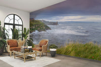 The foreground has green grass and a path along a fence.

