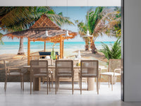 Tropical beach hut wallpaper with palm trees and blue ocean.